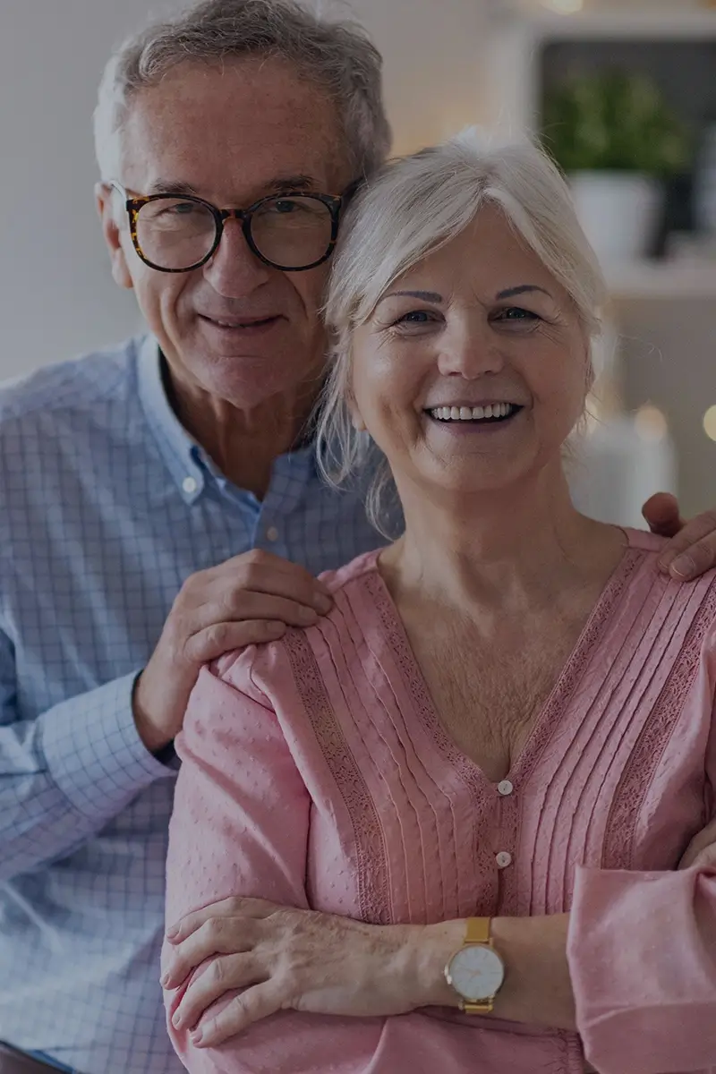 Smiling caregiver supporting elderly man during a walk outdoors